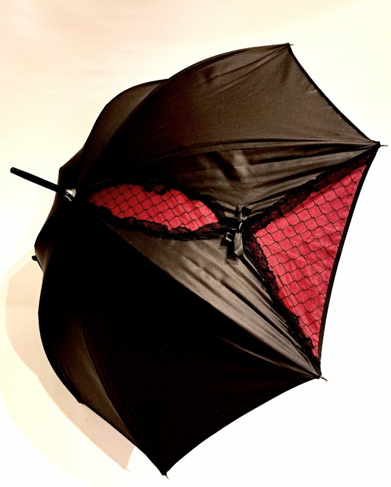 Parapluie Chantal Thomass long noir à noeud et dentelle noire sur fond rose, Gothique chic & anti vent